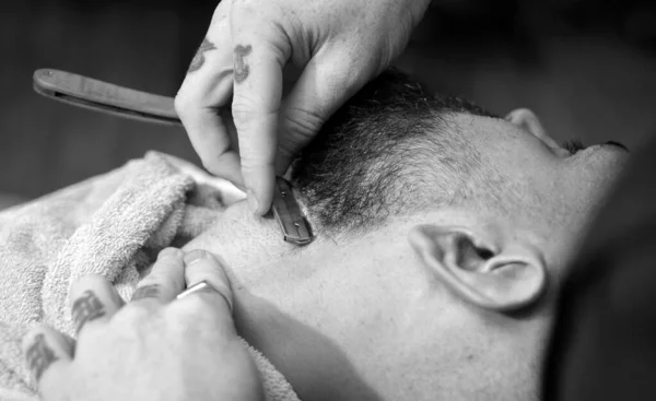 Hair Stylist and Barber. Hairdressers work for a handsome guy at the barber shop. Barber scissors and straight razor barber shop. Male client getting haircut by hairdresser