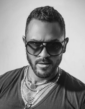 Güneş gözlüklü yakışıklı bir adam. Erkek yüzü. Yakışıklı, erkeksi bir adamın portresi. Gri duvara karşı memnun iş adamının portresi. Güneş gözlüğü. Şehir modası