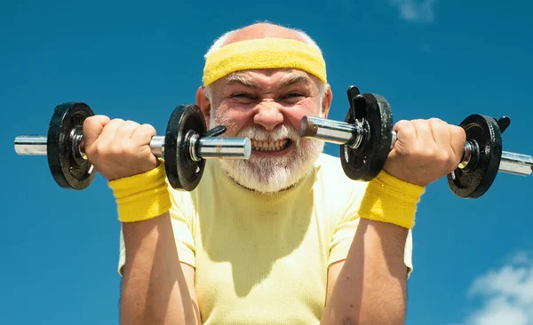 Senior sport man lifting dumbbells in sport center. Health club or rehabilitation center for elderly aged pensioner