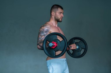 Muscular men lifting weights. Powerful male fit model doing workout in gym. Man lifting dumbells, strong athletic fit man doing exercises with dumbbells. Weightlifting workout. Fitness workout