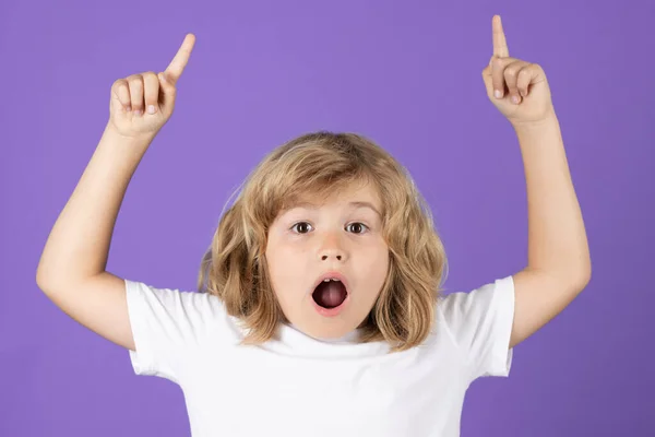 stock image Surprised child pointing up finger on studio background. Shocked kid pointing to copyspace, showing promo offers, points away. Excited emotions, shock, omg and wow expression