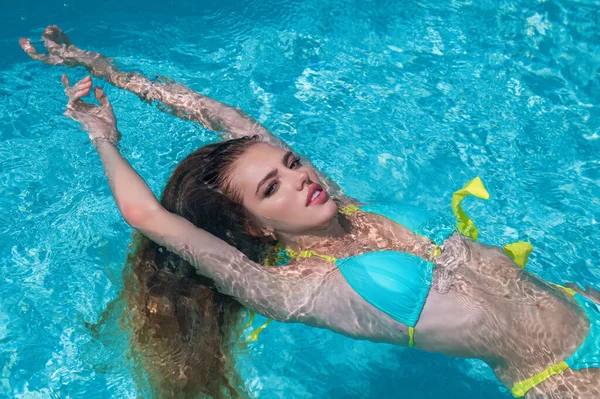 Fashion woman in luxury pool. Elegant sexy woman in the white bikini on tanned slim body posing near swimming pool. Rich summer rest