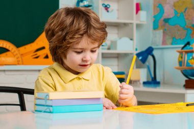 Child home studying and home education. Kid gets ready for school. Back to school. Happy smiling pupil drawing at the desk