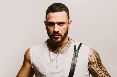 Yakışıklı bir adamın yakın portresi. Gri arkaplandaki modaya uygun Latin adamın yüzünü kapat