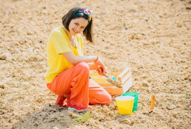 Happy girl having fun with shovel and plant in pot. Planting seedlings. Little helper in garden Planting flowers. Child farmer concept