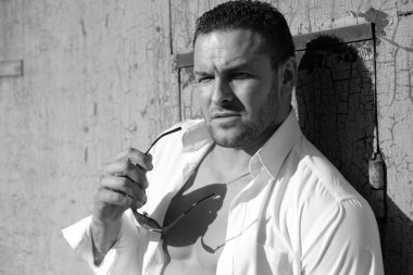 Kendine güvenen yakışıklı adam. Erkek vahşi tarzı. Beyaz gömlekli ve güneş gözlüklü çekici bir adam.