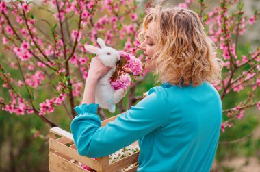 Beautiful young woman with bunny rabbit on farm. Happy easter