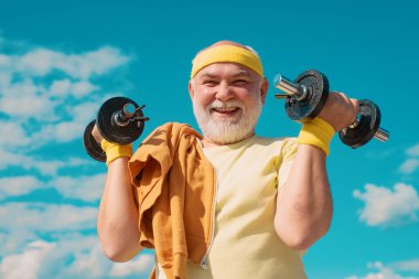 Happy senior man with dumbbell looking at camera. Grandfather exercising with dumbbell. Sport for senior man