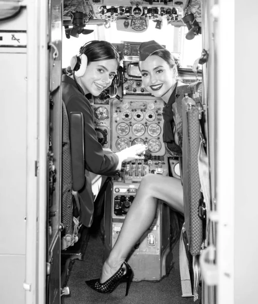 飞机驾驶舱的女驾驶员和飞行教官 美丽的微笑年轻的女飞行员坐在飞机机舱里 带耳机的年轻貌美女飞行员的画像 — 图库照片