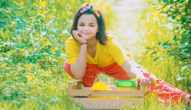 Portrait of kid gardener carrying harvested in farm. Child spend time in the orchard. Child farmer in the farm with countryside background