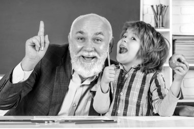 Öğrenci ve öğretmen sınıfta. Büyükbaba ve oğul birlikte eğleniyorlar. Olgun erkek öğretmen ve öğrenci balkon arka planında