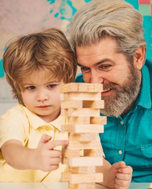 Father and son playing stacking wood blocks Jenga games for meditation practice. Children building wood blocks at home.