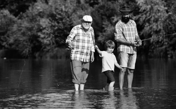 釣りだ 幼い少年は父親と祖父と一緒に湖で釣りをする 幸せな祖父と孫が川で釣りをしている 男性趣味 — ストック写真