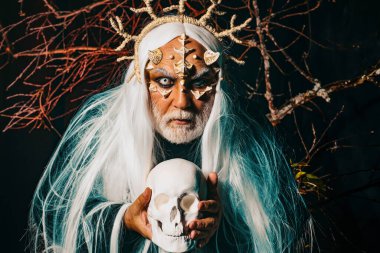 Man wizard with skull. Devil horror concept. Bearded old man dressed like Halloween monster. Man with a bull head. Vampire man with white eyes