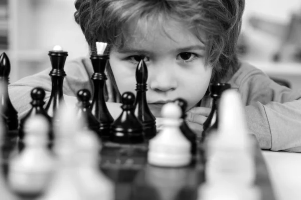 Little boy playing chess. Kids educational games, child early development. Boy think or plan about chess game, vintage style for education concept