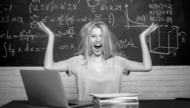 Sıkılmış öğrenci bir dizüstü bilgisayar ile hat üzerinde ev ödevi yapıyor. Öğrenci sınıfta okumaktan yoruldu. Lise. Negatif yüz ifadesi. Dizüstü bilgisayar üzerinde çalışan mutsuz öğrenci. Öğrenme