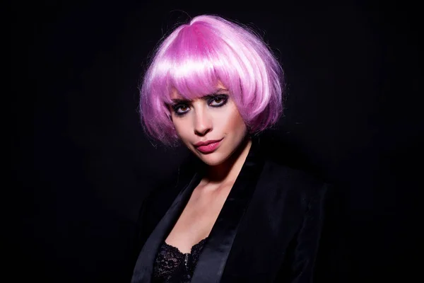 Hair wigs concept. Portrait of beautiful woman over black background. Funny woung girl in wig. Fashion, art and creativity concept. Gourgeos, sexy, young model, looking seductive at camera in pink wig