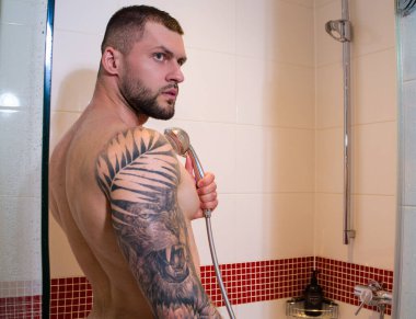 Portrait of sexy naked man taking shower in bathroom. Male hygiene routine. Sexy man with wet muscular body washing in the shower. Guy in the shower bath. Man taking hot shower. Morning routine clipart