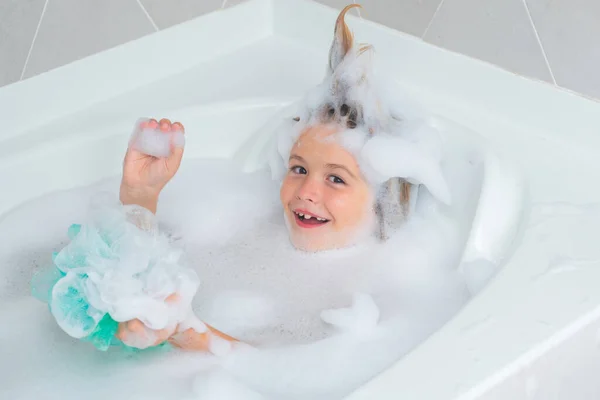 Little Child Taking Bubble Bath In Beautiful Bathroom With Big Garden View  Window. Kids Hygiene. Shampoo, Hair Treatment And Soap For Children. Kid  Bathing In Large Tub. Baby Boy With Foam In