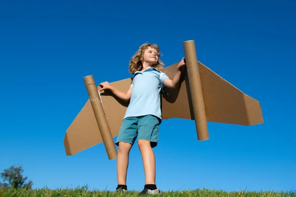 段ボールおもちゃの飛行機の翼で遊ぶ子供の男の子は テキストのためのコピースペースを空にクラフト 家族との創造と空飛ぶ概念の夢 — ストック写真