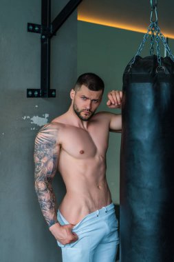 Seksi, çıplak, sportif vücut. Spor salonunda güçlü bir boksör. Spor kulübünde kum torbasıyla spor erkek antrenmanı. Genç adamın fitness antrenmanı var. Erkek sporcu spor yapar.