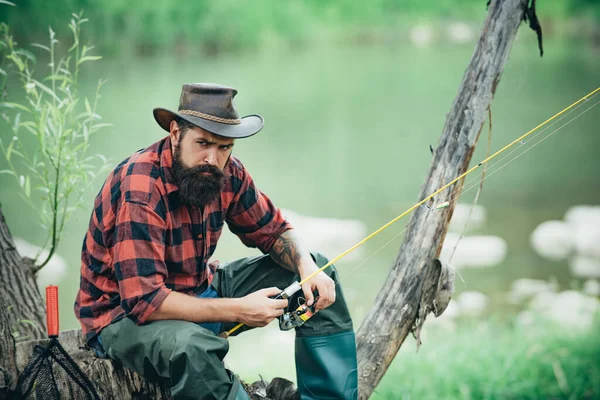 一个留着胡子的年轻人在湖边或河里钓鱼 — 图库照片