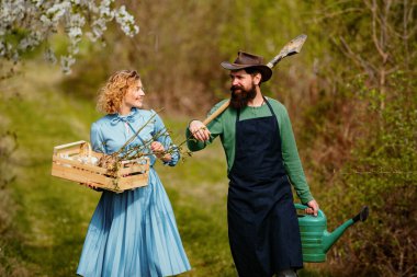 Bir çift çiftlik, tarla boyunca sebze ve sebze dolu kutular taşır.
