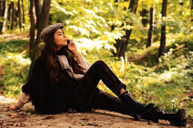 Romantik Sonbahar Kadın Modeli. Fall Maple Leaf Outdoor ile mükemmel kadın modası modeli. Sarı Ağaçlar ve Yapraklar. Sonbahar kırmızı elbiseli güzel moda kadını doğanın arka planında yapraklar dökülüyor.