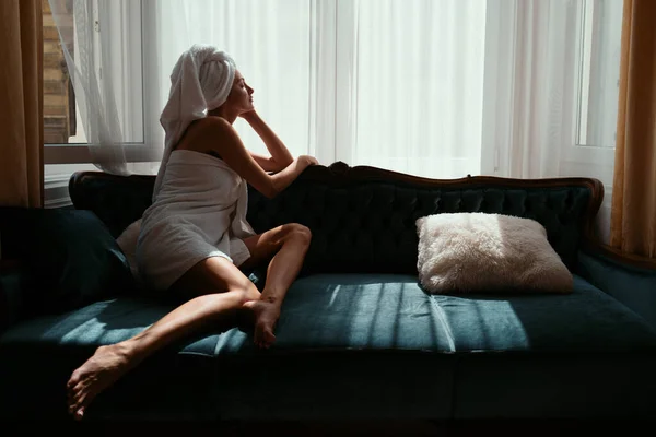 豪華な寝室の居心地の良いソファベッドで女の子の休憩と敷設は簡単な朝 ホテルの部屋でバスローブとタオルを着てリラックスした魅力的なセクシーな女性 素敵な優しさガールフレンド — ストック写真