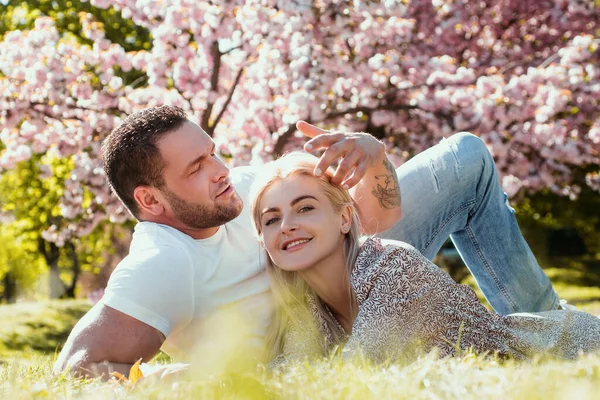 春天里相爱的一对快乐的情侣 两个年轻人在樱花中放松 微笑的情人在公园里放松 家庭胜于自然 关系和日期 — 图库照片