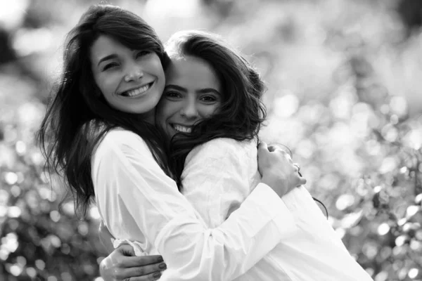 Friends forever. Two cute lovely girl friends posing with smile on green spring background