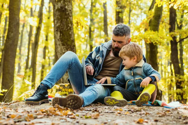 Ecology upbringing. Father teaches son use modern technology. United with nature. Ecology lesson. Forest school and ecology education. Man bearded father and little son with laptop in forest.