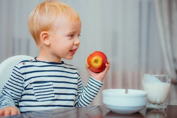 孩子吃粥 孩子可爱的男孩蓝眼睛坐在桌子与盘子和食物 健康食品 男孩可爱的婴儿吃早餐 婴儿营养 吃得健康 在家吃零食的幼儿 健康营养 — 图库照片