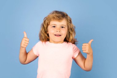 Child showing thumbs up on studio isolated background. Portrait of kid boy making thumbs up sign