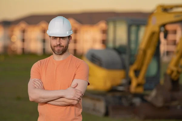 在建筑工地安装挖掘机的建筑工人 大楼里有建筑工人的机械拖拉机 挖掘机牵引机和建筑工人建筑工地上戴头盔的建筑商 — 图库照片