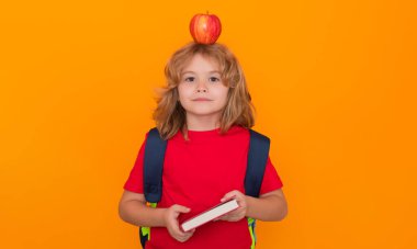 Akıllı çocuk, zeki okul çocuğu. Stüdyonun sarı arka planında izole edilmiş bir öğrenci. Okula dönelim. Kafada elma, fikir kavramı.