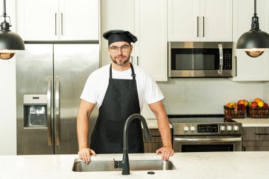 Aşçı şapkalı adam mutfakta yemek pişiriyor.