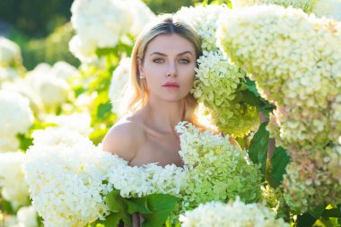 Yaz parkında çiçek açan ortancada poz veren şehvetli bir kadın. Rahatlama, seyahat, özgürlük ve bahar tatili kavramı. Moda tarzı. Romantik ve yaşam tarzı kavramı