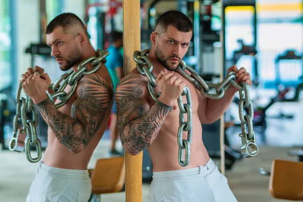 セクシーな筋肉の男は彼の筋肉をポンプし ジムで体重のスポーツメタルチェーンを持ち上げます 鎖で運動する強いフィットマン 筋肉の若いハンサムな男の重みを持ち上げる ウェイトリフティングとトレーニング — ストック写真