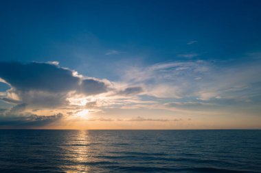 Tropikal deniz okyanusunda gün batımı ve gündoğumu bulutları. Seyahat tatili afişi. Manzara gökyüzü ve yansıma ışınları. Alacakaranlık, denizde alacakaranlık. Sakin, altın gökyüzü arka planı