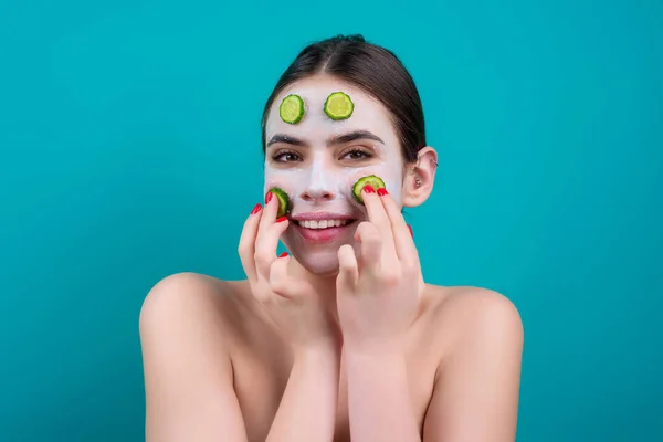 Woman with facial mask with slices of fresh cucumber on face. Cosmetic procedure. Beauty spa and cosmetology. Spa woman applying facial clay mask. Beauty treatments