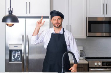 Yemek pişirme ve aşçılık konsepti. Mutfakta üniformalı aşçı. Erkek aşçı ya da önlüklü aşçı. Aşçının bereli portresi. Yemek pişirme konsepti