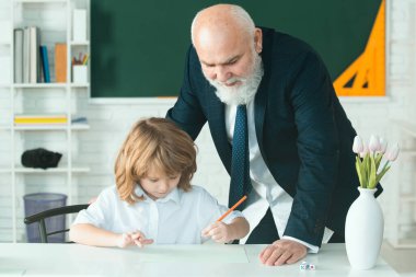 Öğretmen öğrenmeye yardımcı olur. Öğrenci çocuk sınıfta öğreniyor. Eğitim, öğretmenlik. Öğrenci çocuk dersi.