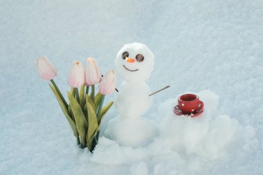 Merhaba ilkbahar, güle güle kış. Kahve fincanlı kardan adam. Çiçekli kardan adam