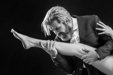 Takım elbiseli garip bir işadamı kadın bacakları yalıyor. Ayak fetişisti. Lüks ve ataerkil düzen. Erkek bacak yalar.