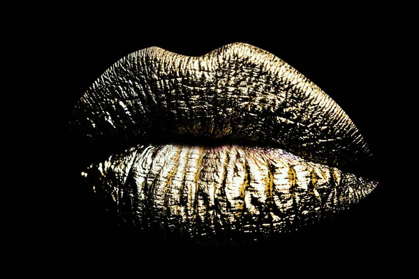 Closeup gold lips. Woman sexy golden lip makeup isolated on black background
