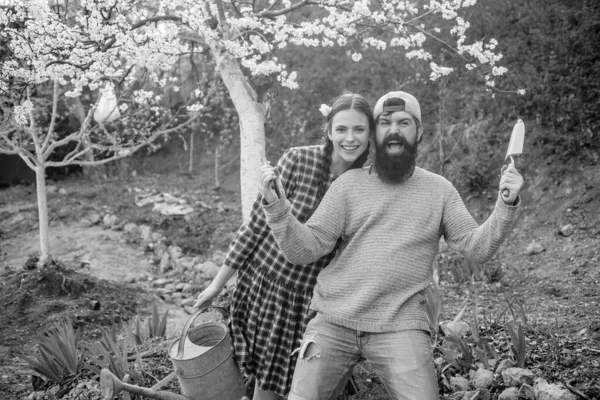 春の自然の背景に庭のツールを保持する面白い庭師のカップル ガーデンツール付きの庭師のカップル ショベルと白人男性農家の肖像 — ストック写真