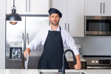 Aşçı, aşçı ya da fırıncı portresi. Aşçı şapkalı ve aşçı üniformalı adam mutfakta yemek pişiriyor.