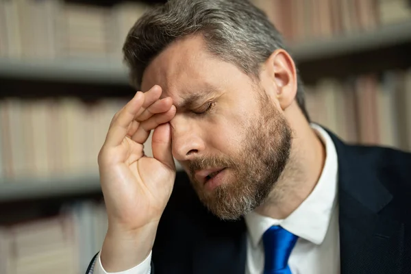 頭痛片頭痛のあるストレスのある男の肖像画を閉じます 疲れたビジネスマンは残業して頭痛がしている 職場でノートパソコンを持っている男は頭痛に苦しんでいます 過労からの片頭痛 — ストック写真