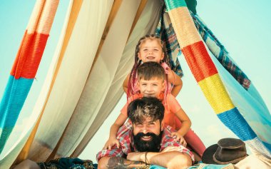 Çocuklar başlarını babalarıyla dikey bir sıraya koyarlar. Çatıdaki küçük piramit evi aileyle eğlenmek için. Genç yakışıklı baba boş zamanlarını çocuklarla geçiriyor.